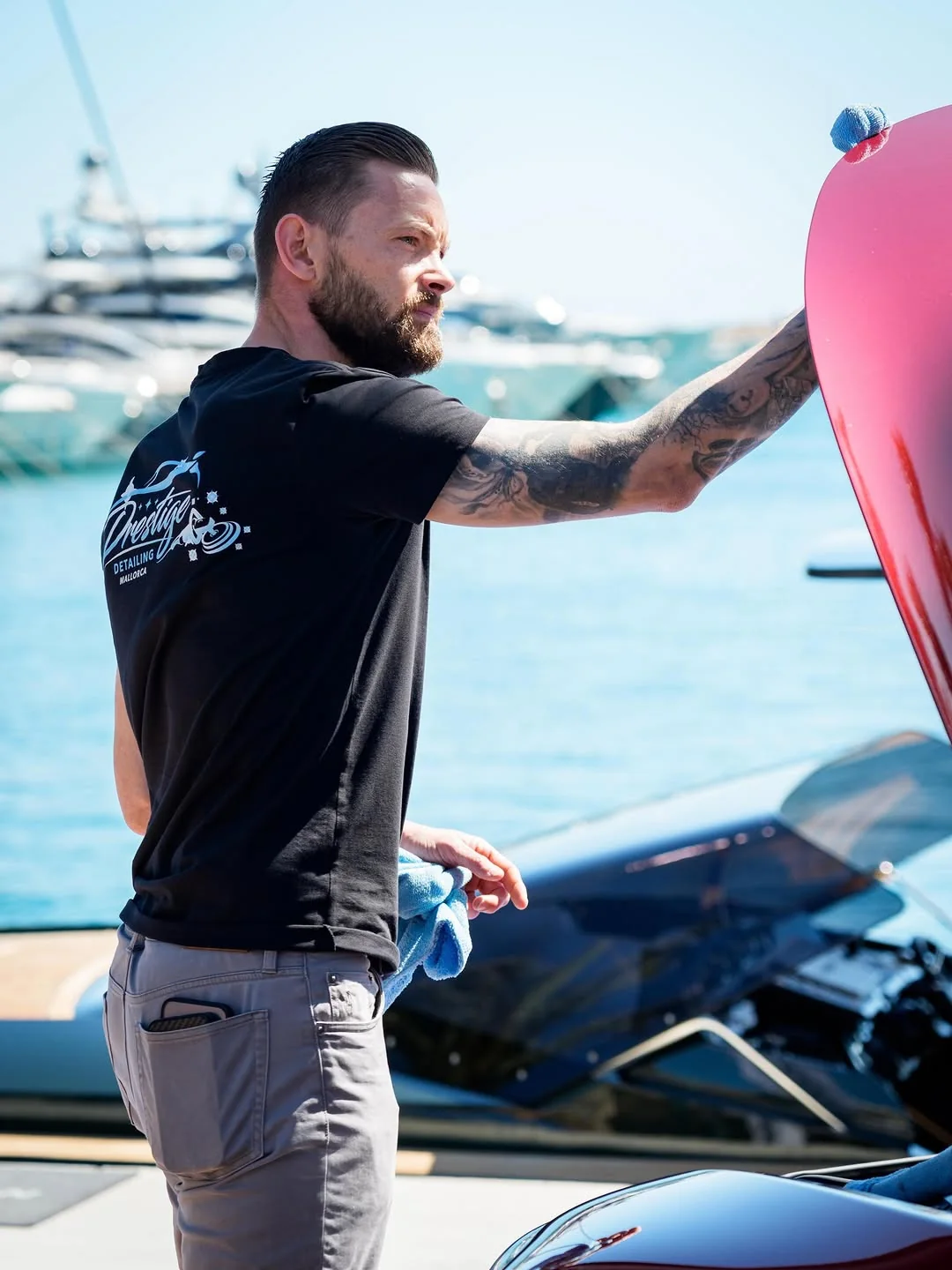 Prestige Detailing Mallorca bei der Arbeit an einem roten Sportwagen im Hafen